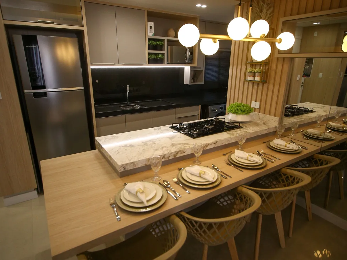 Cozinha planejada com bancada em pedra, cooktop e armários até o teto