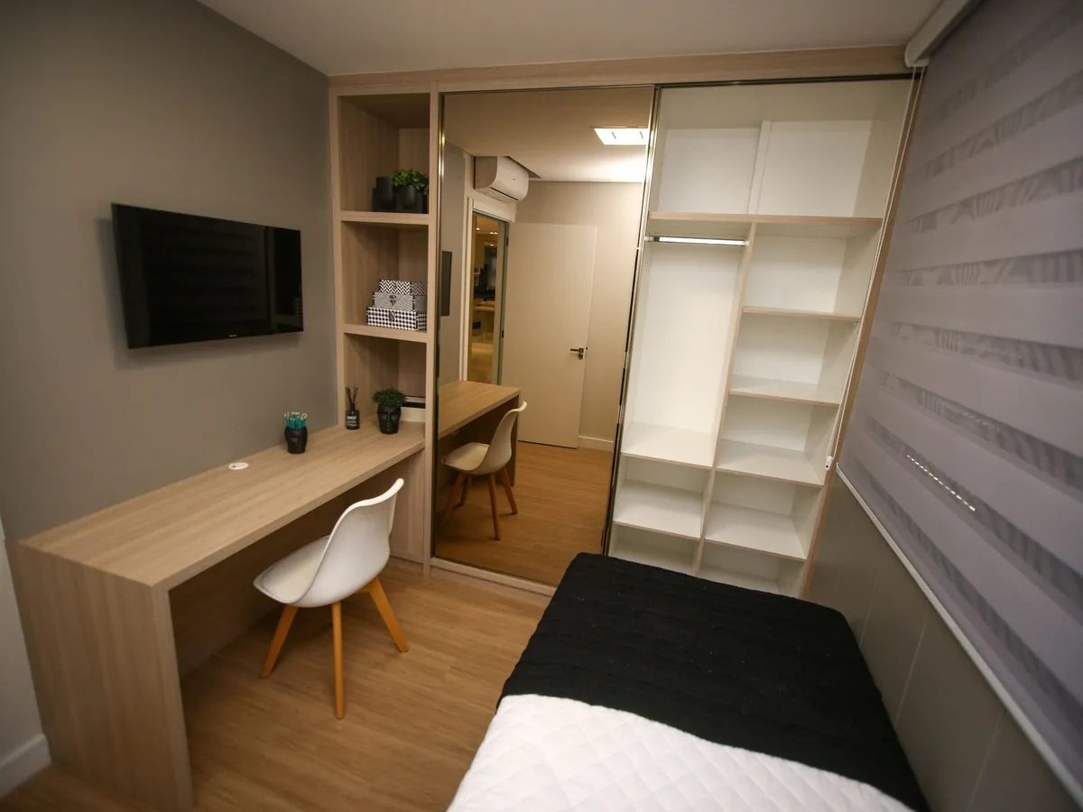 Home office com bancada, cadeira e closet aberto de prateleiras brancas